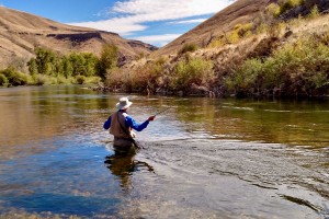 An angler with a delicate trout fly fishing outfit out in pursuit of wild trout in beautiful mountain strewn river surroundings.